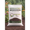A 50 lb bag of Vermicastings Worm Castings Bulk by Dancing Spirits Farm, displayed on a bed of dark compost with blurred garden foliage in the background.